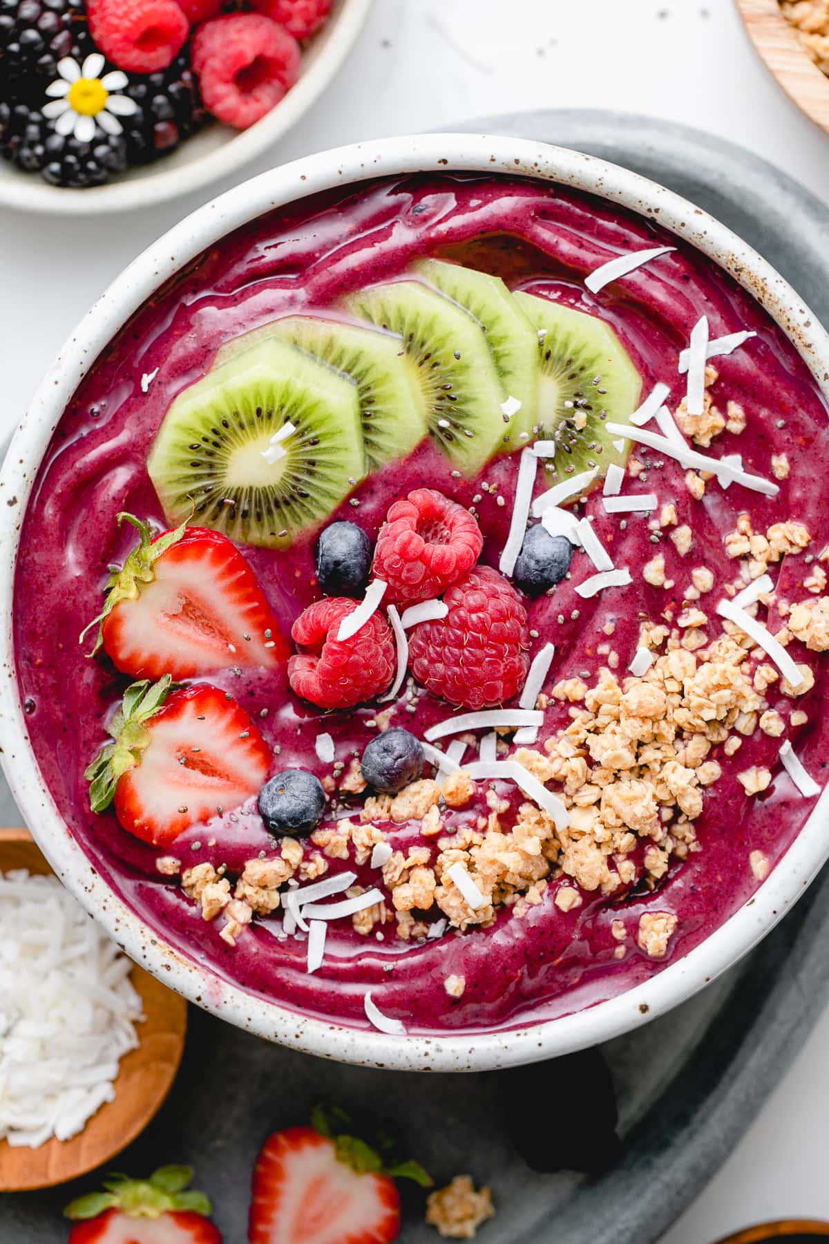 top down view of homemade acai bowl topped with healthy toppings with items surrounding.