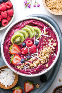 top down view of homemade acai bowl topped with healthy toppings with items surrounding.