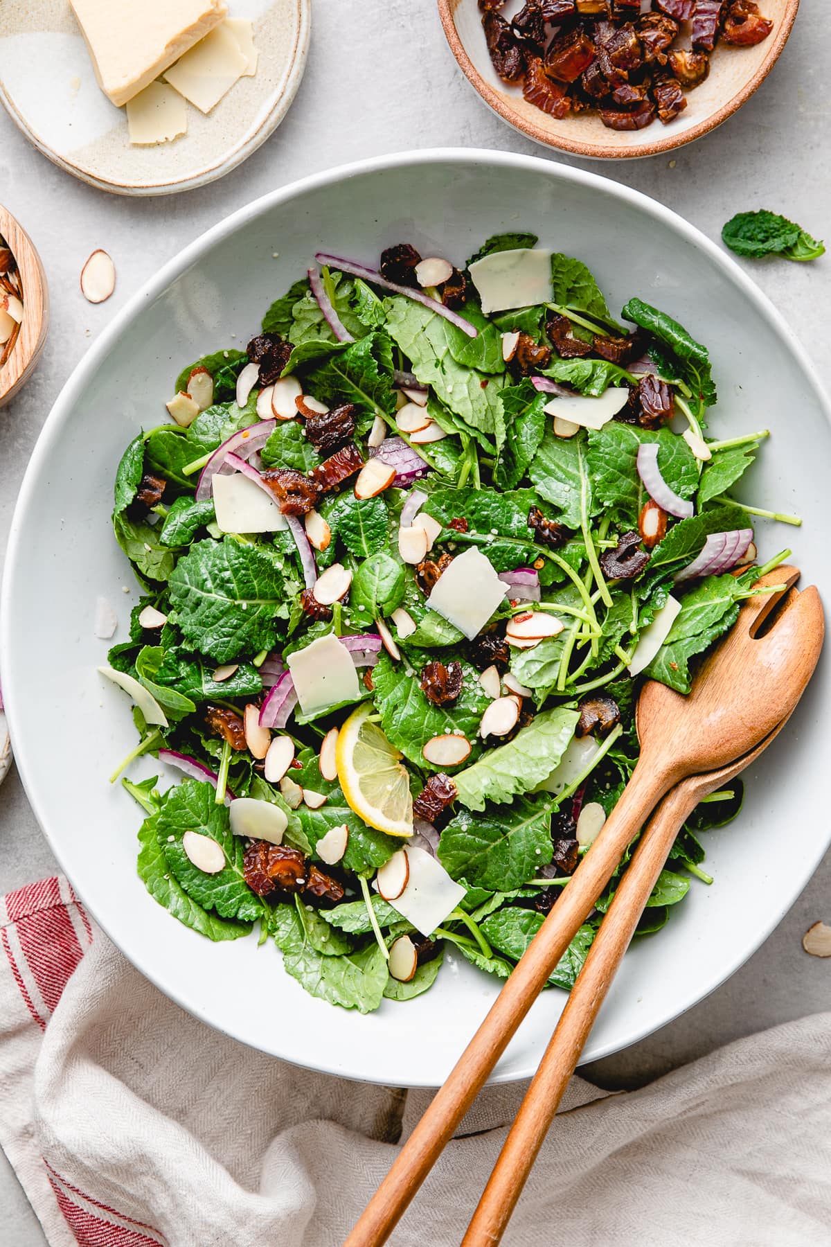 top down view of freshly made kale salad with dates and almonds in bowl with items surrounding.