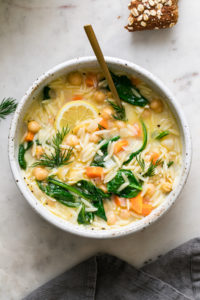 top down view of bowl with healthy serving of chickpea orzo lemon soup with spoon.