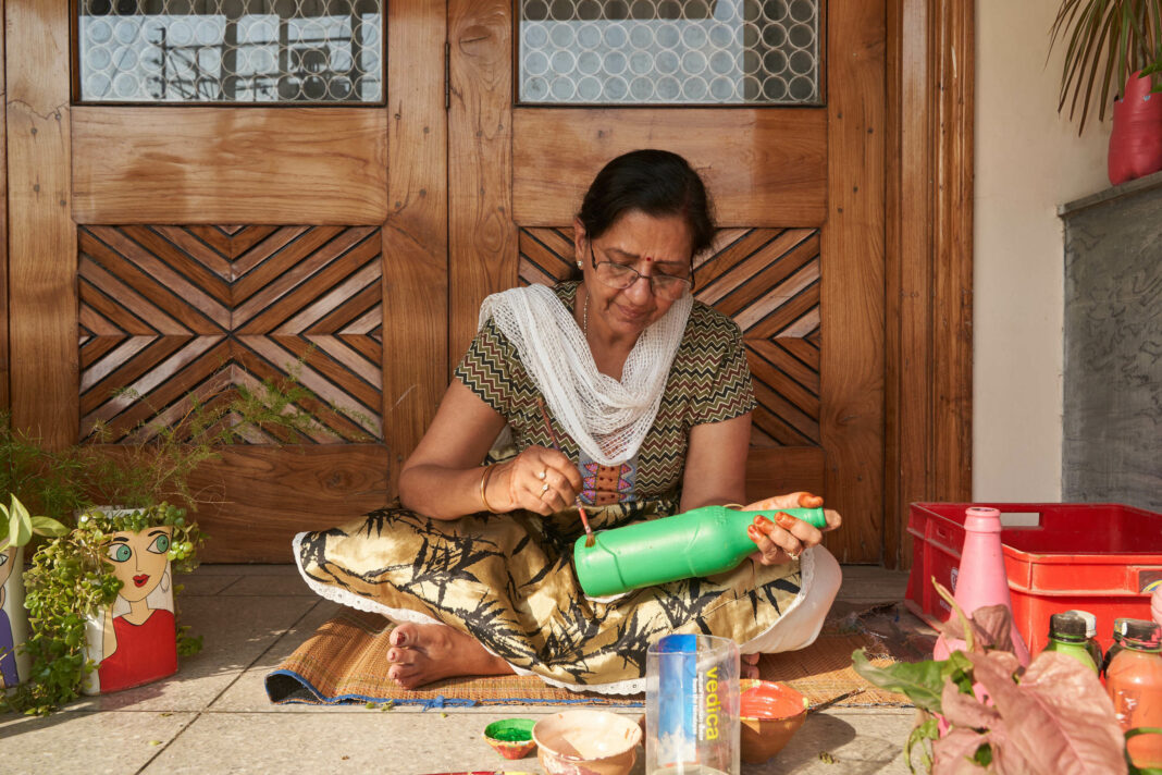 Woman repaints an old bottle.