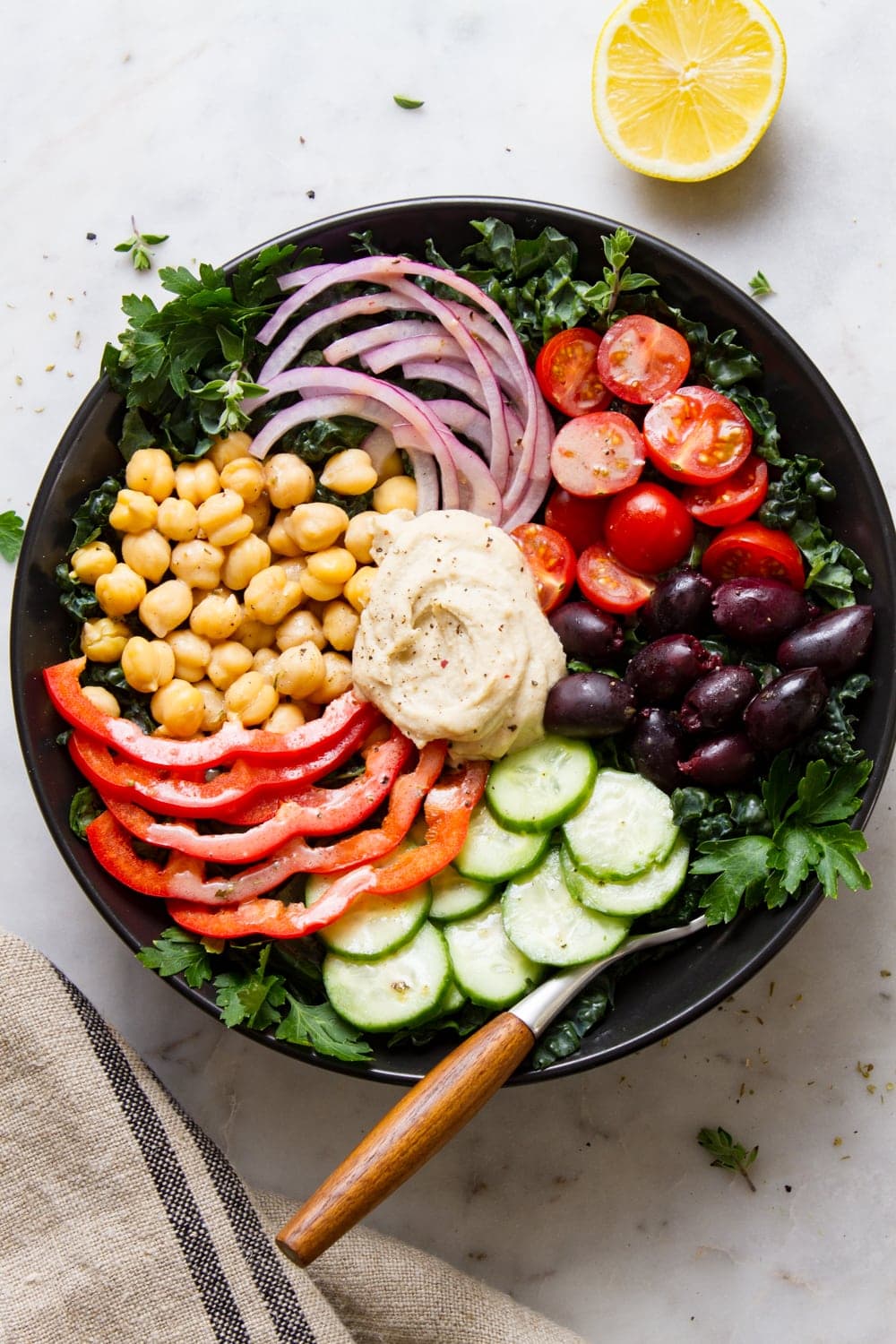 top down view of mediterranean kale salad in a black bowl.