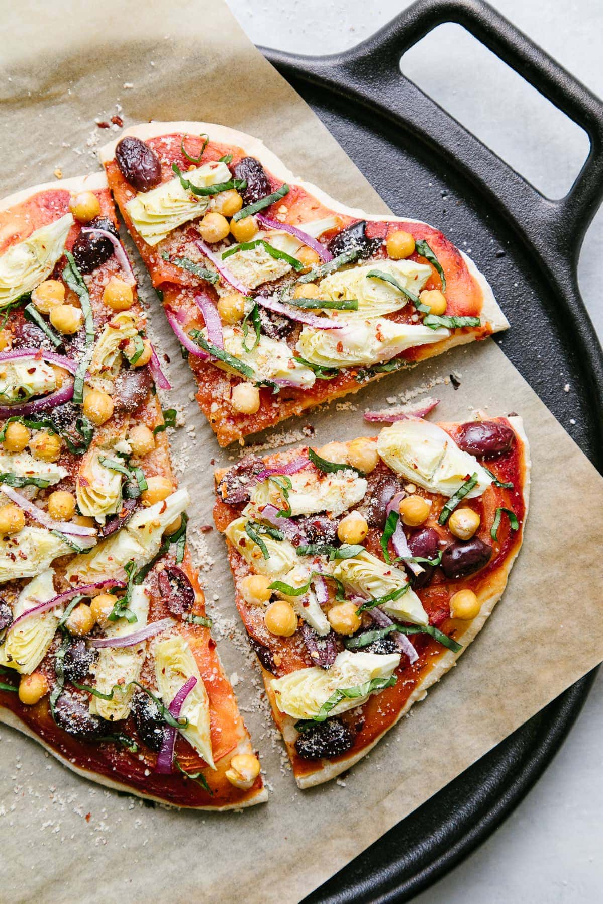 top down view of mediterranean pizza sliced on a cast iron pizza pan.