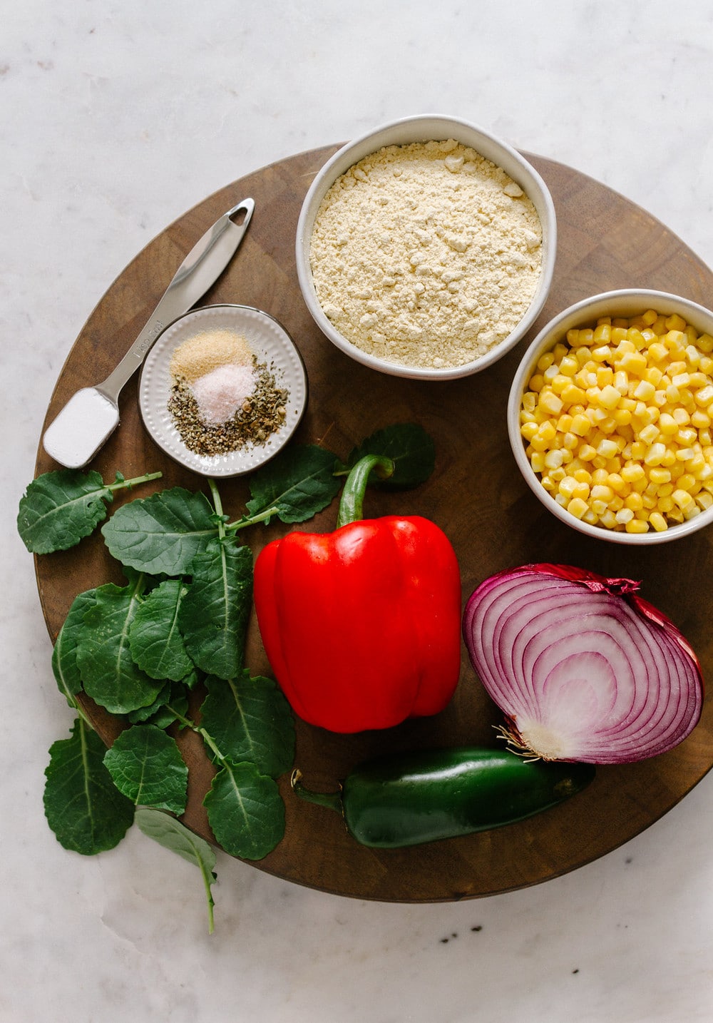 top down view of chickpea flour frittata muffin ingredients on a round wooden cutting board.