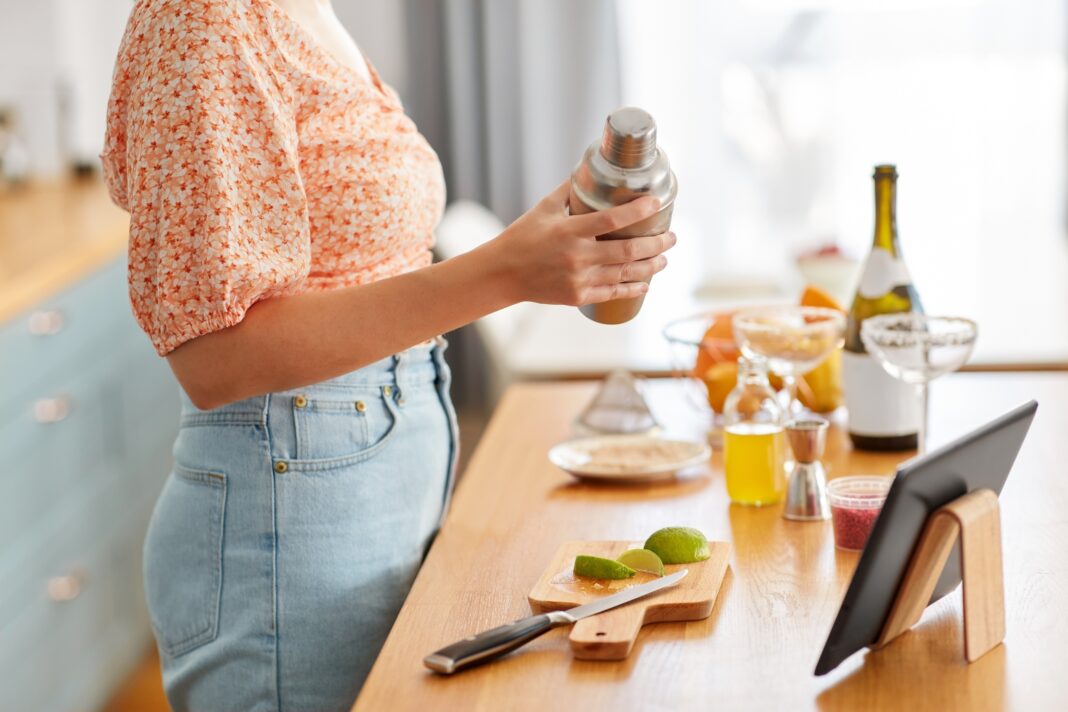 A woman making a cocktail in the kitchen.