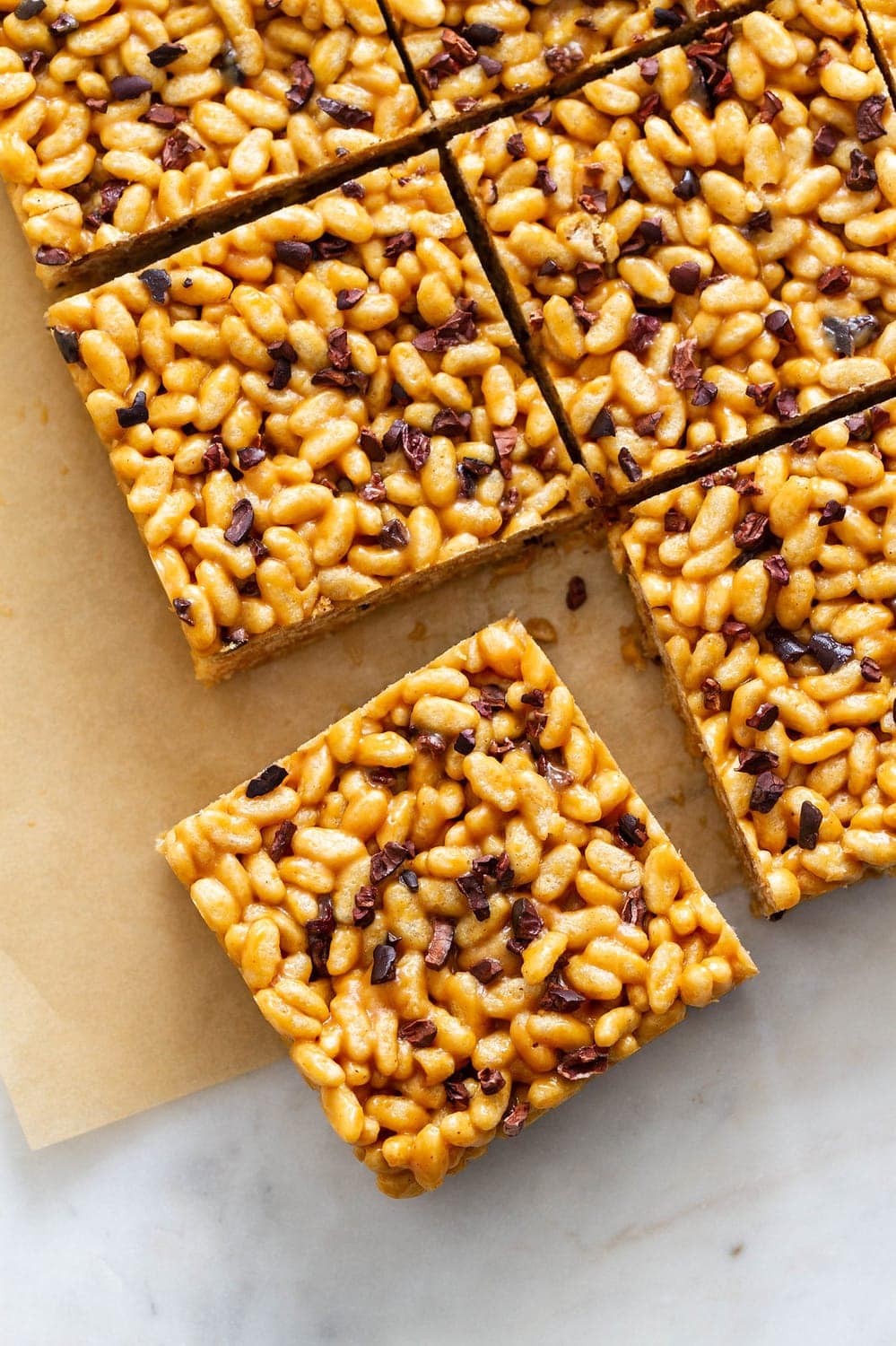 top down view of peanut butter cacao nibs rice crispy treats on parchment paper sliced into squares