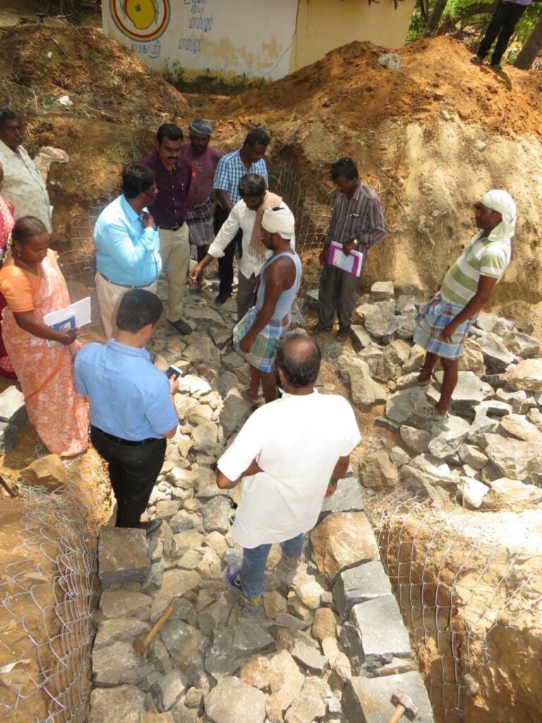 group of people looking at stones at project site for well