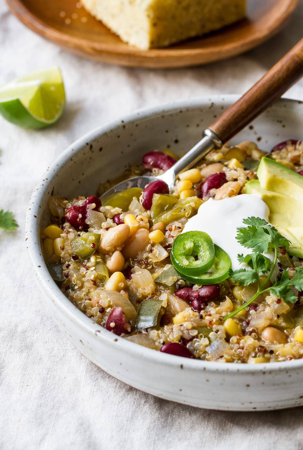 side angle view of a bowl full of quinoa verde chili with spoon.