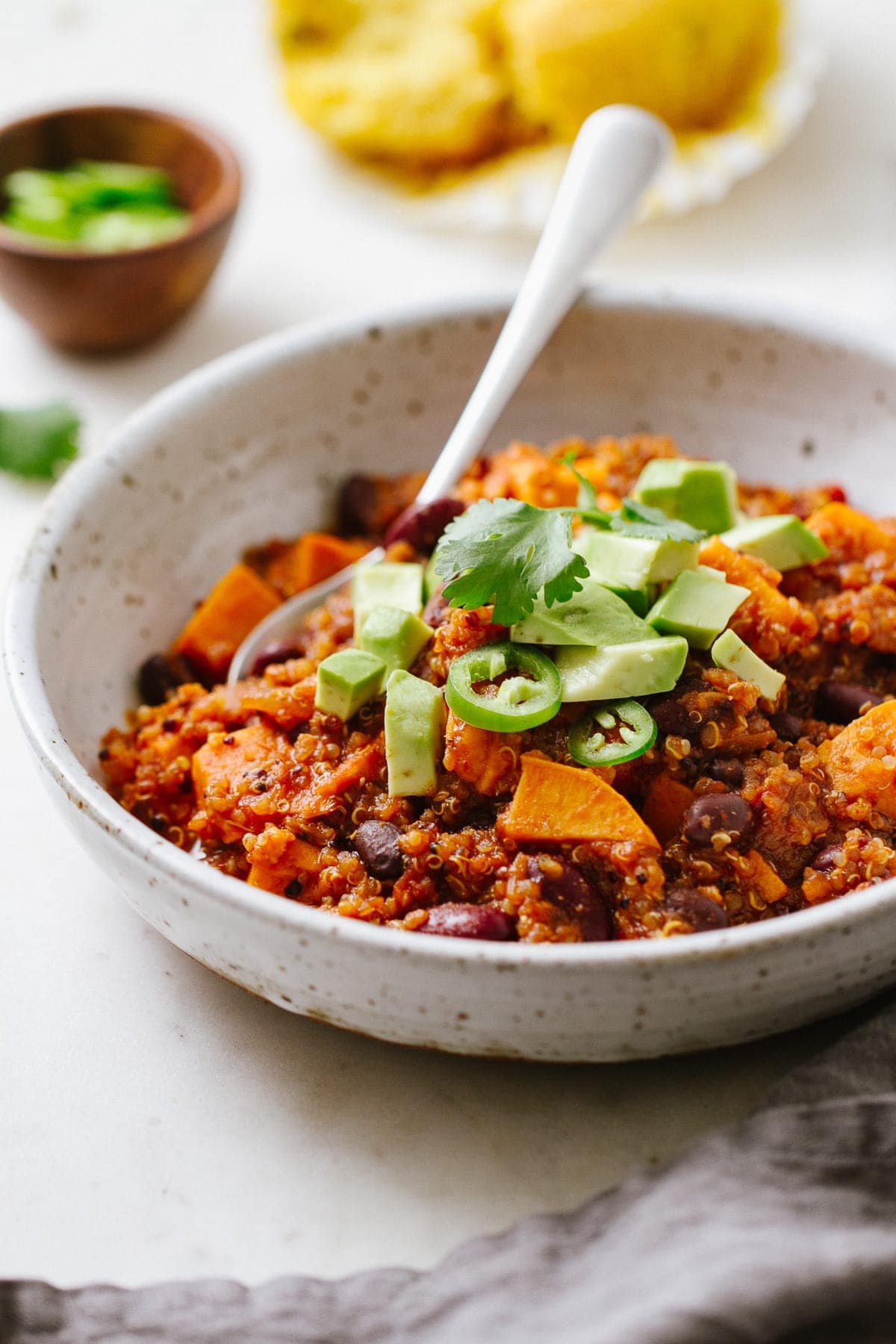 side angle view of a bowl with a serving of healthy vegan sweet potato quinoa chili with spoon.