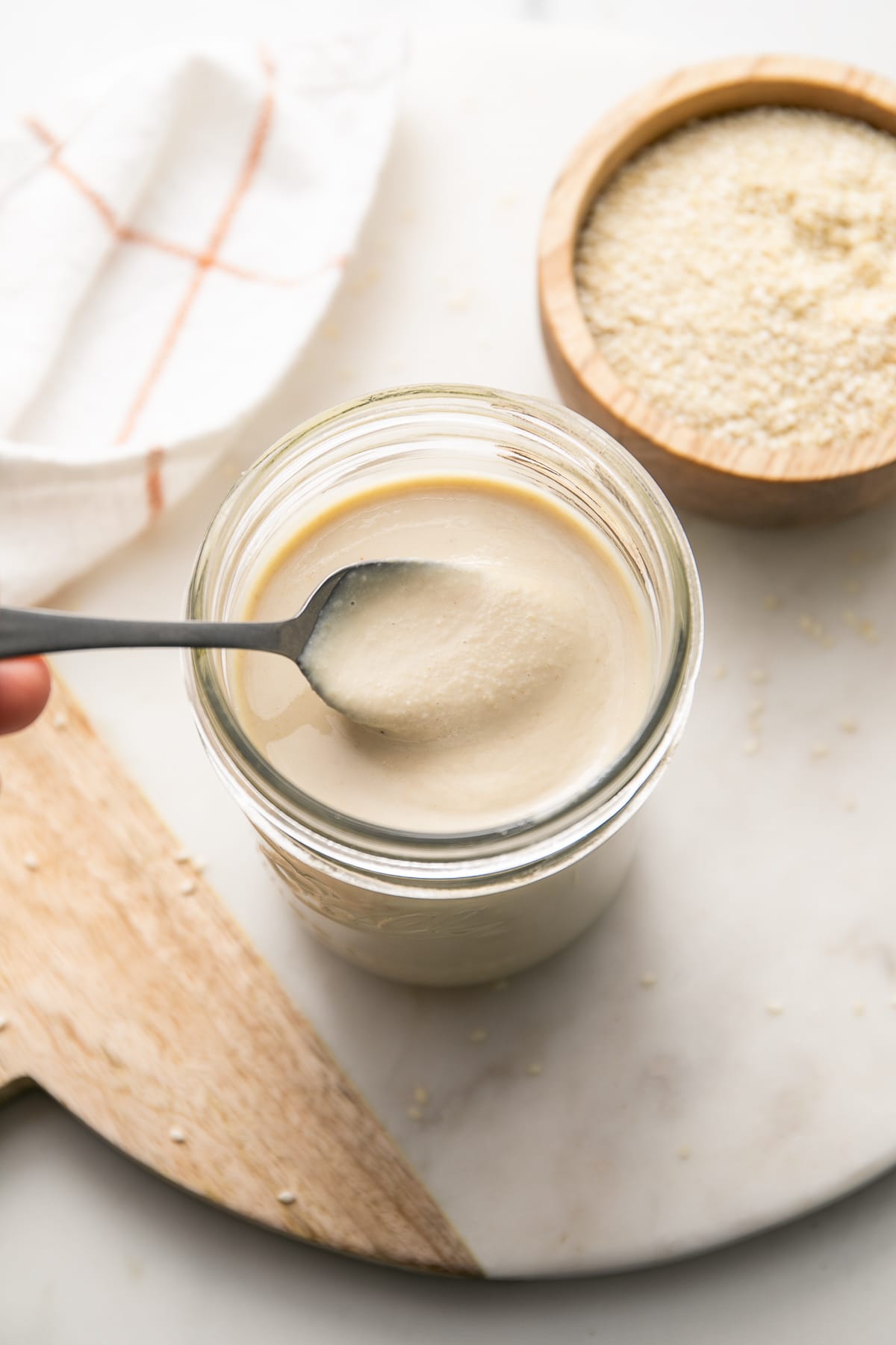 top down view of spoon in tahini with items surrounding.