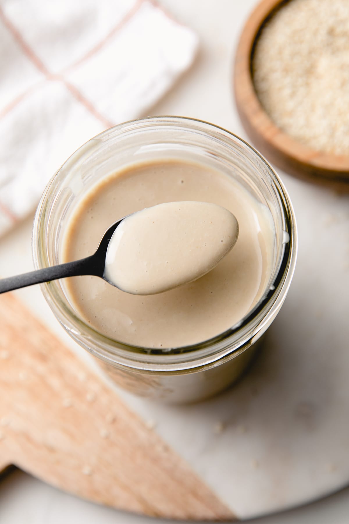 top down view of spoon in tahini with items surrounding.