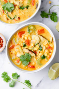 top down view of plated thai coconut curry corn soup with items surrounding.