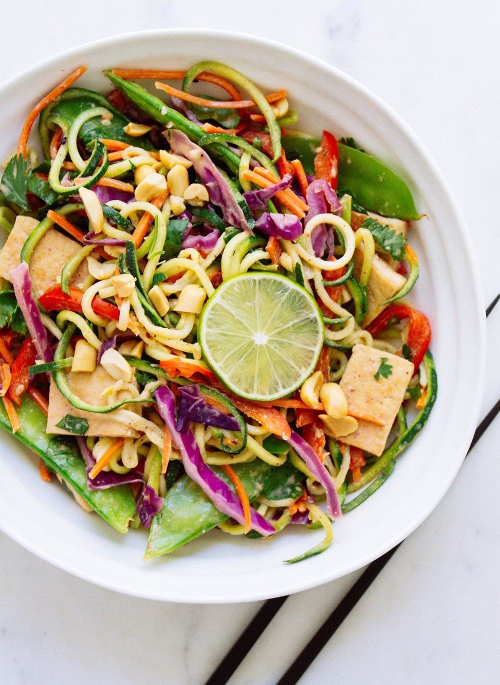 thain zucchini noodles with crispy tofu and veggies in a white bowl