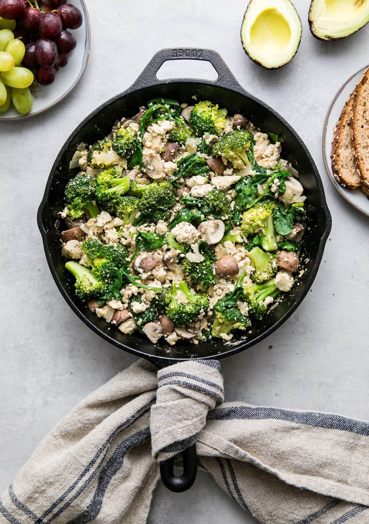 top down view of freshly made tofu scramble with veggies, dijon and tarragon in a skillet with items surrounding.