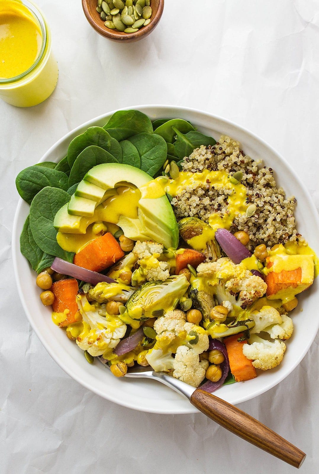 top down view of roasted cauliflower and sweet potato nourish bowl drizzled with turmeric tahini dressing.