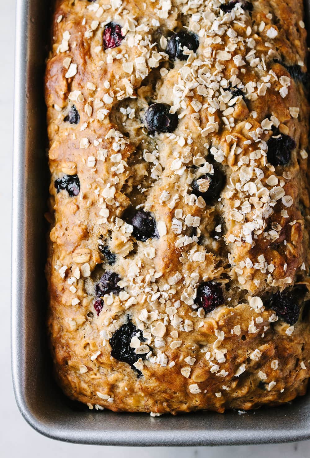 top down view of freshly baked vegan blueberry banana oat bread in loaf pan