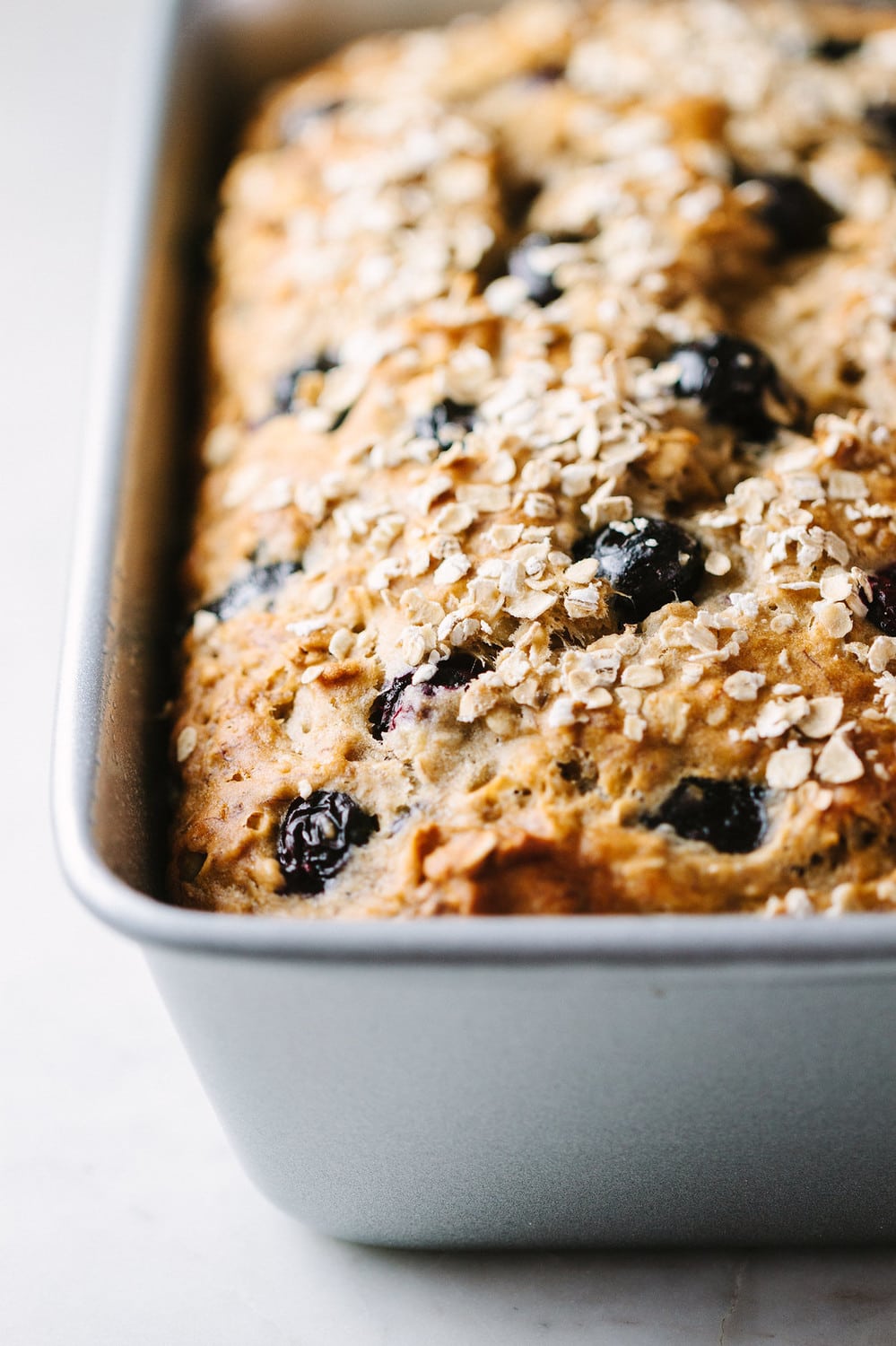 vegan blueberry banana oat bread in a loaf pan just baked