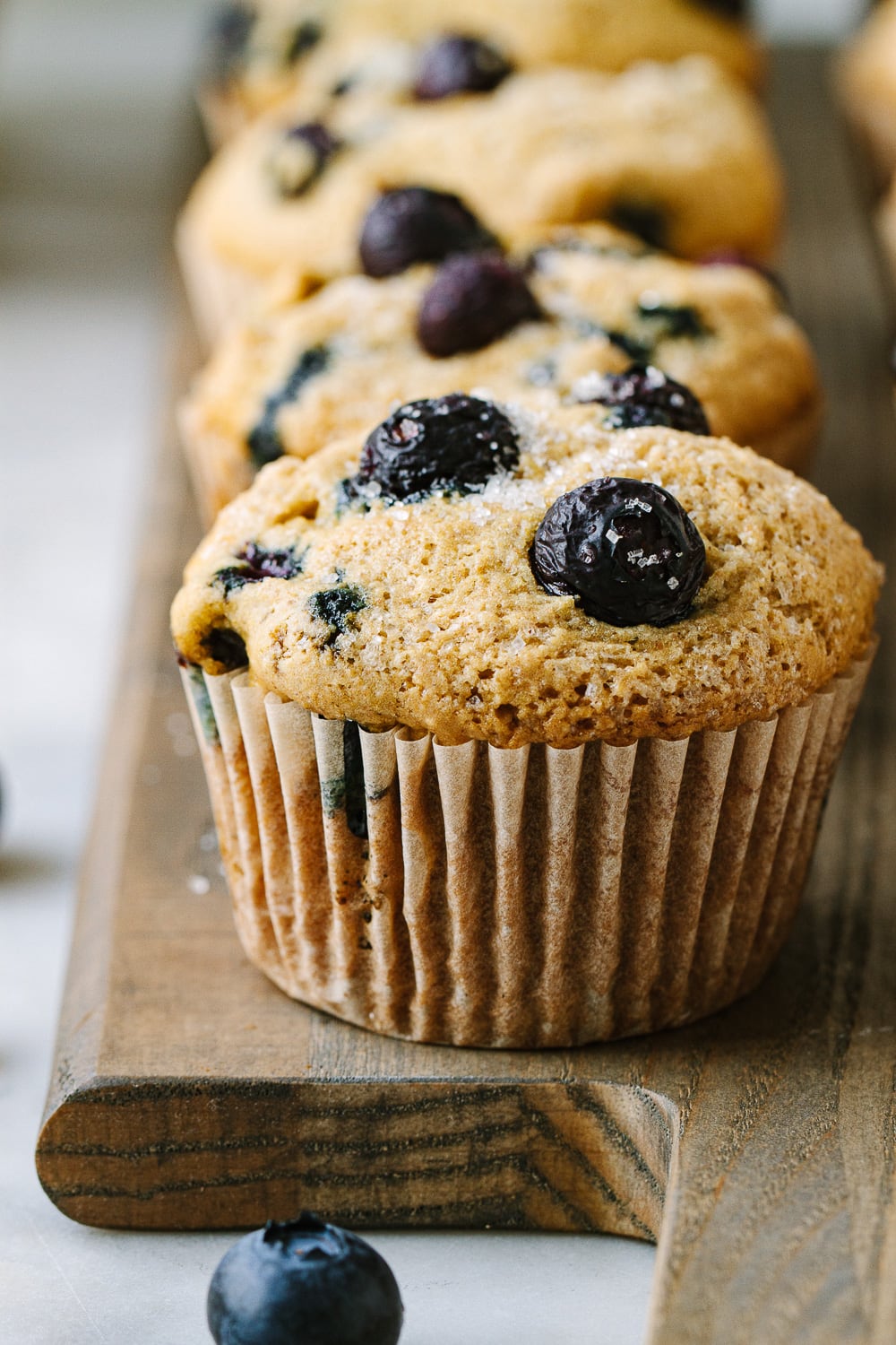 head on shot of vegan blueberry muffins on a wooden serving board.