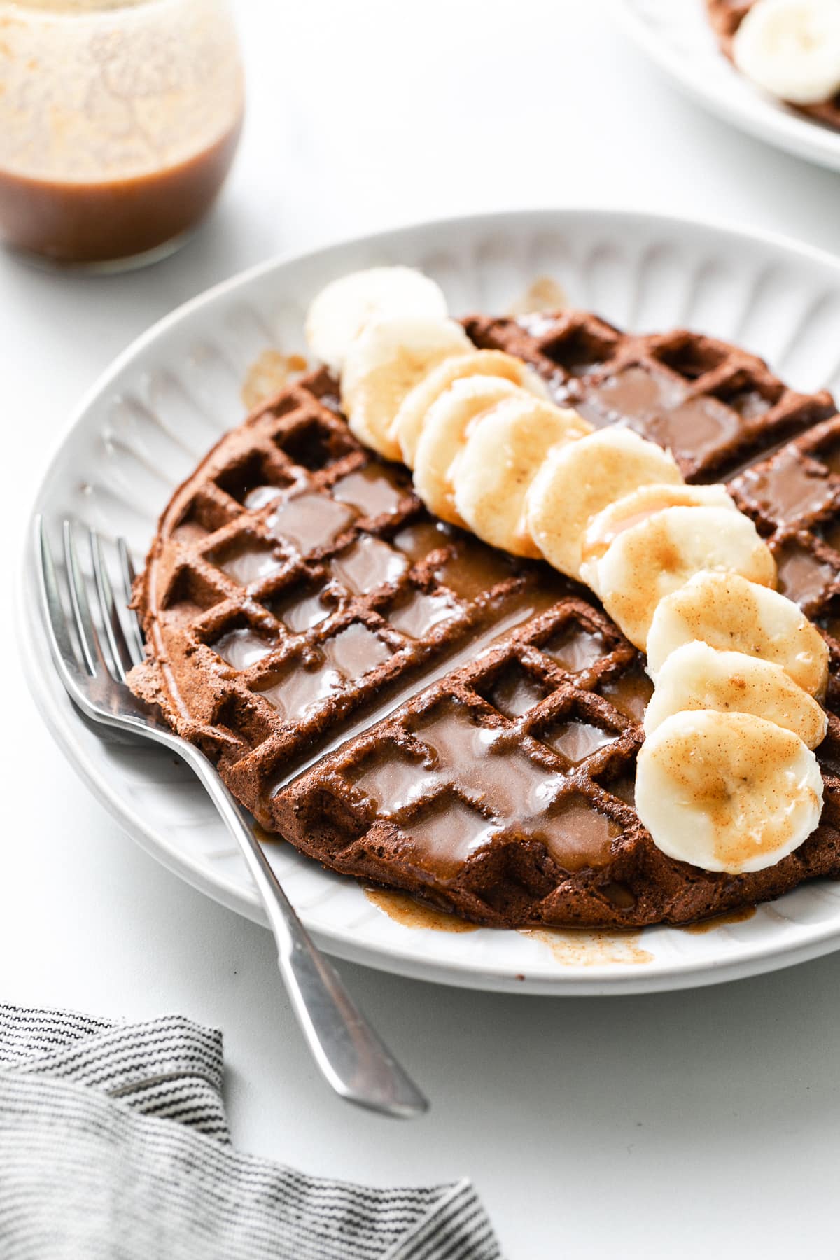 side angle view of chocolate vegan buckwheat waffles with banana and syrup.