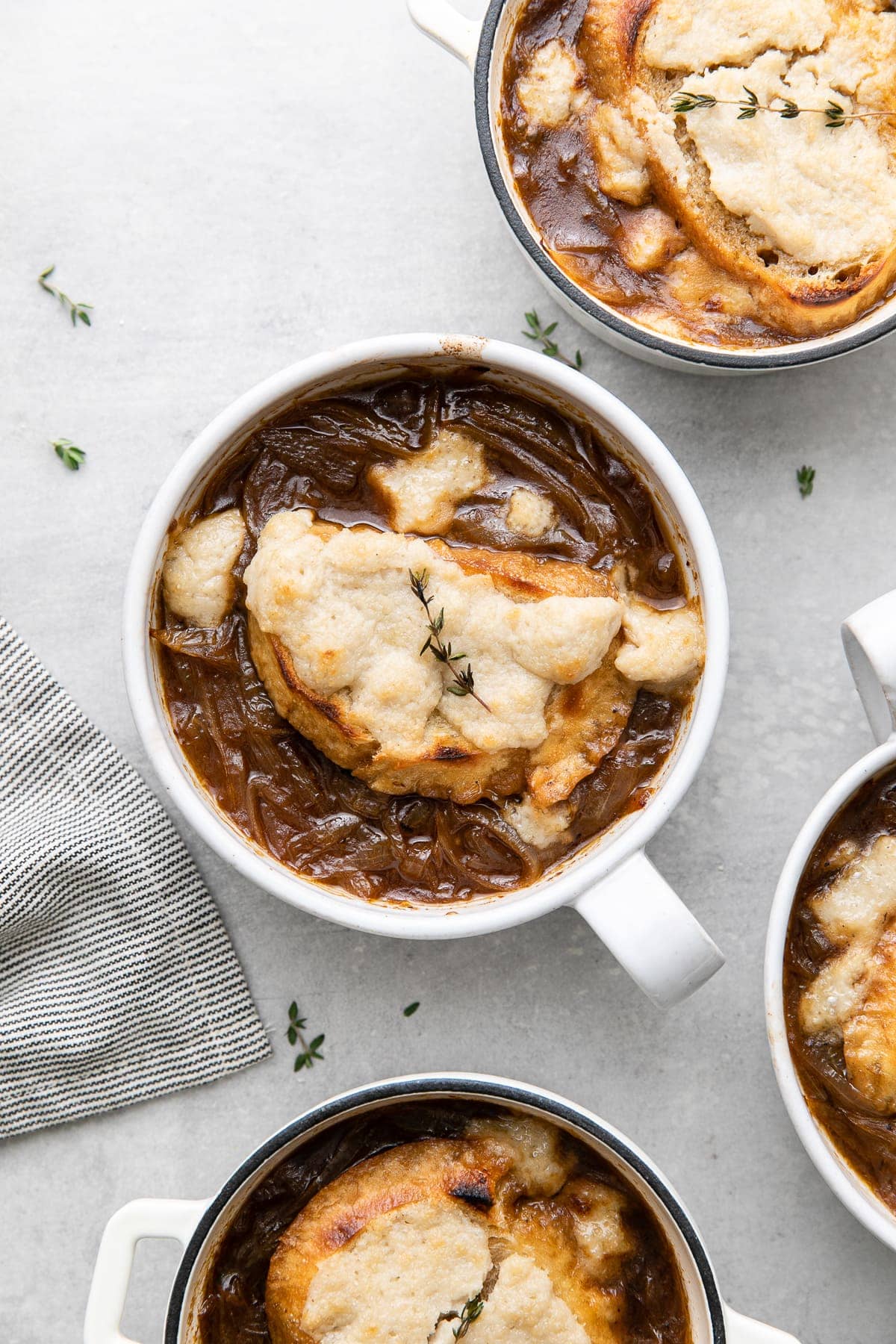 top down view of baked french onion soup in bowls and mini dutch ovens ready to eat.