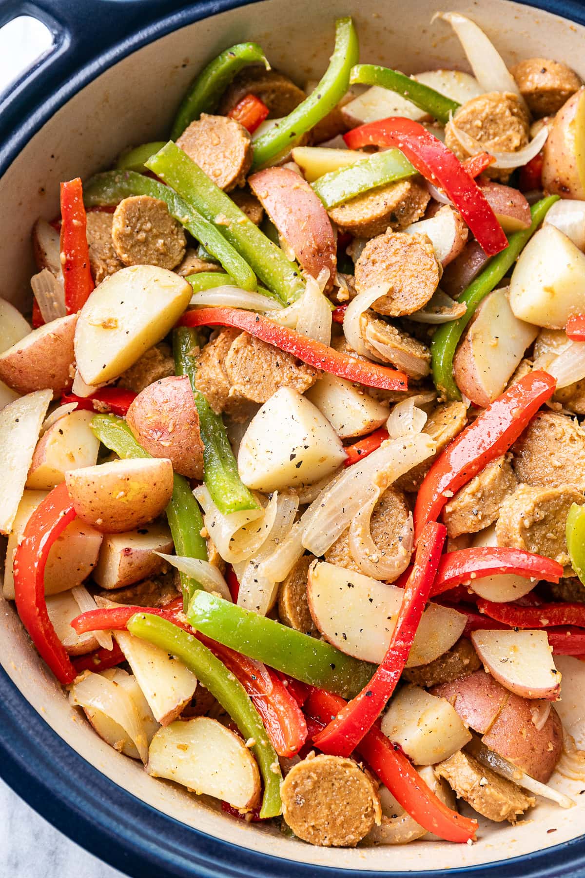 top down view of freshly made vegan kielbasa sausage with potatoes and peppers in a pot.