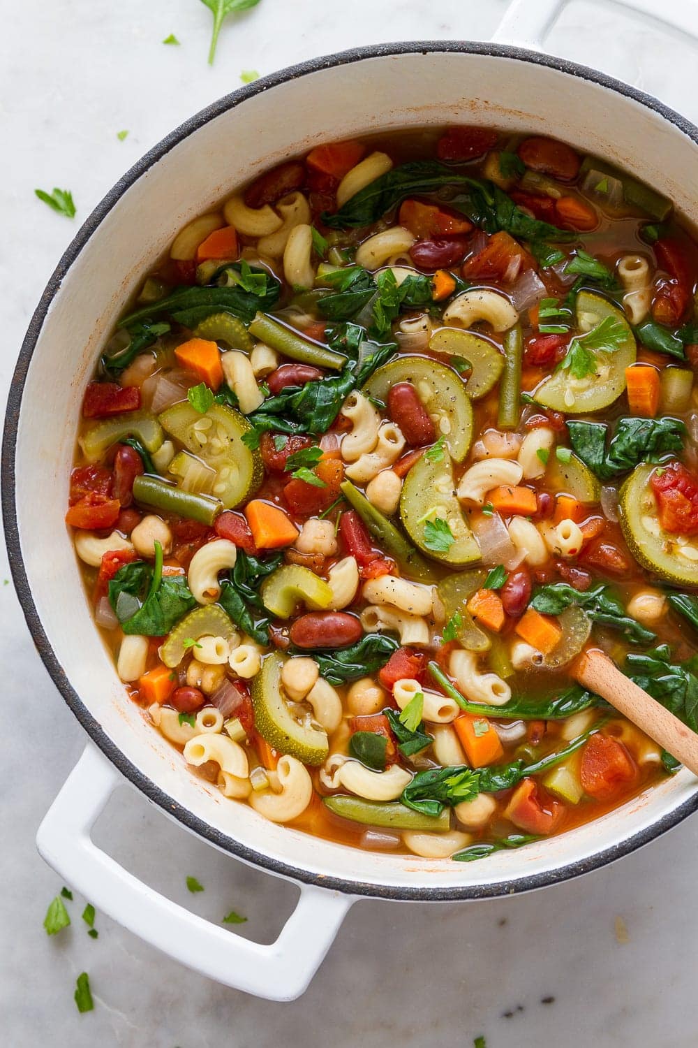 top down view of a pot full of freshly made easy vegan minestrone with wooden spoon.