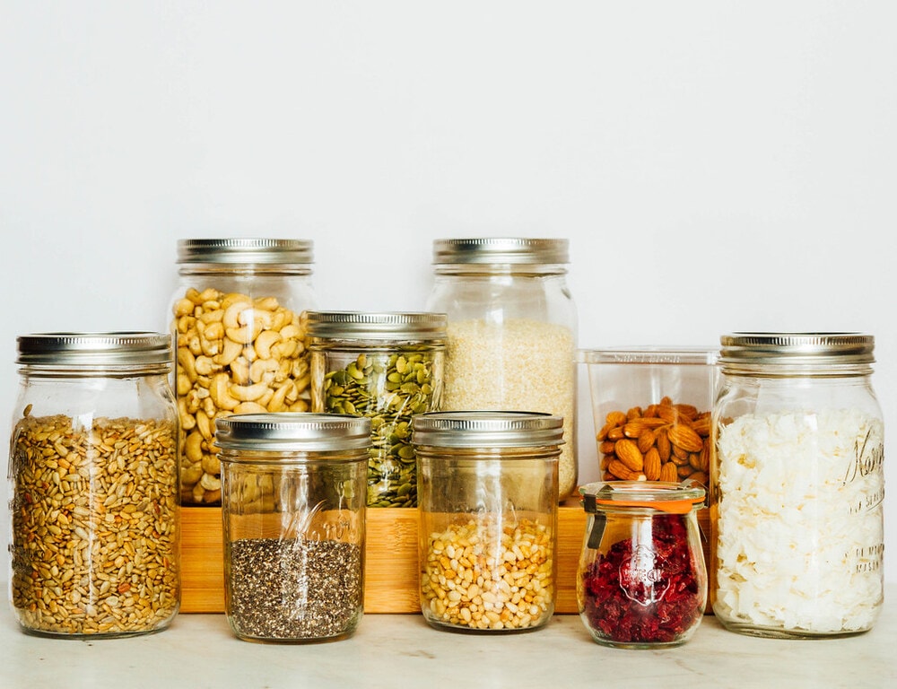 mason jars filled with an assortment of dried nuts, seeds, and dried fruits.