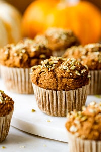 head of view of freshly made vegan pumpkin muffins resting on a serving board.