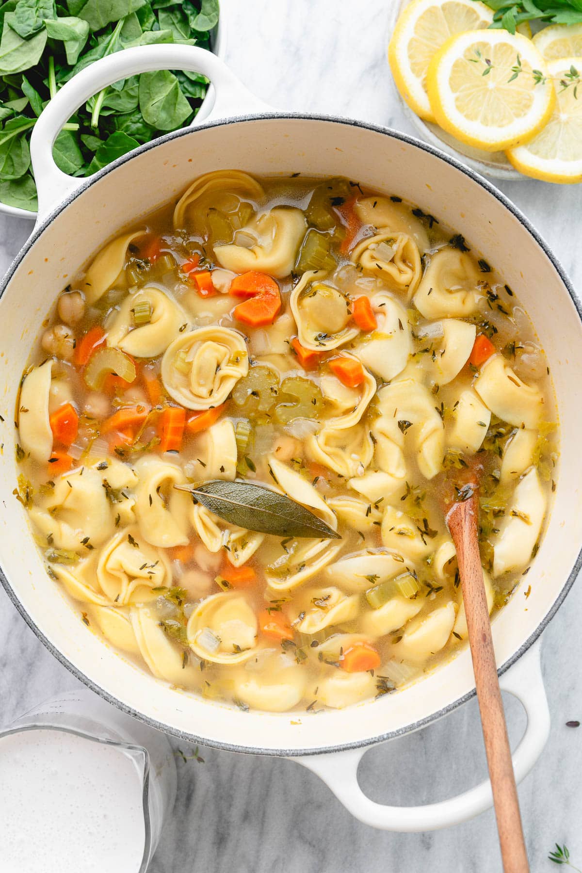 top down view of white pot with cooked tortellinis and veggies with items surrounding.