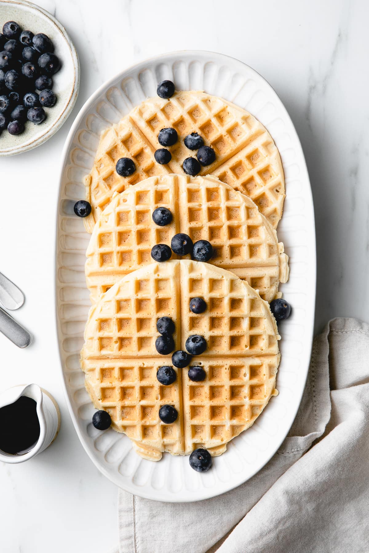 top down view of best vegan waffles on a serving platter with items surrounding.