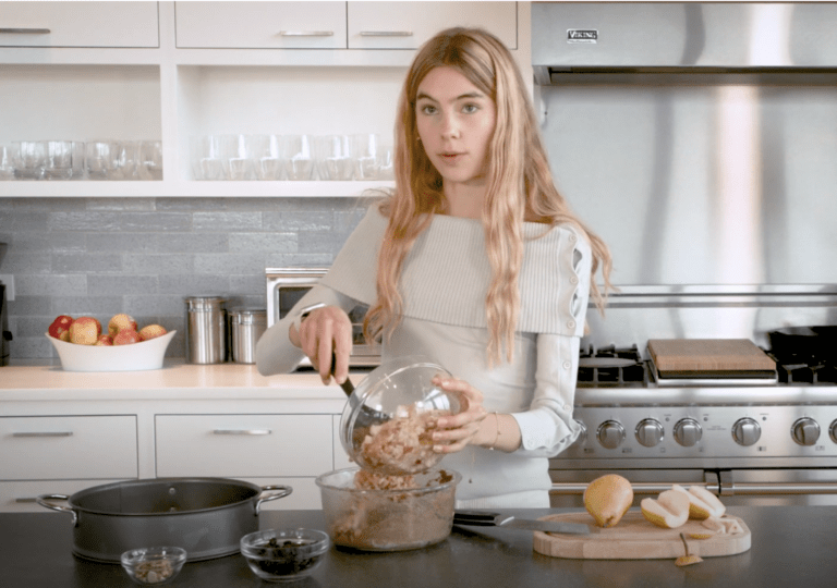 Cleo is in the Bluedot Kitchen adding grated pears to a bowl with her cake batter.